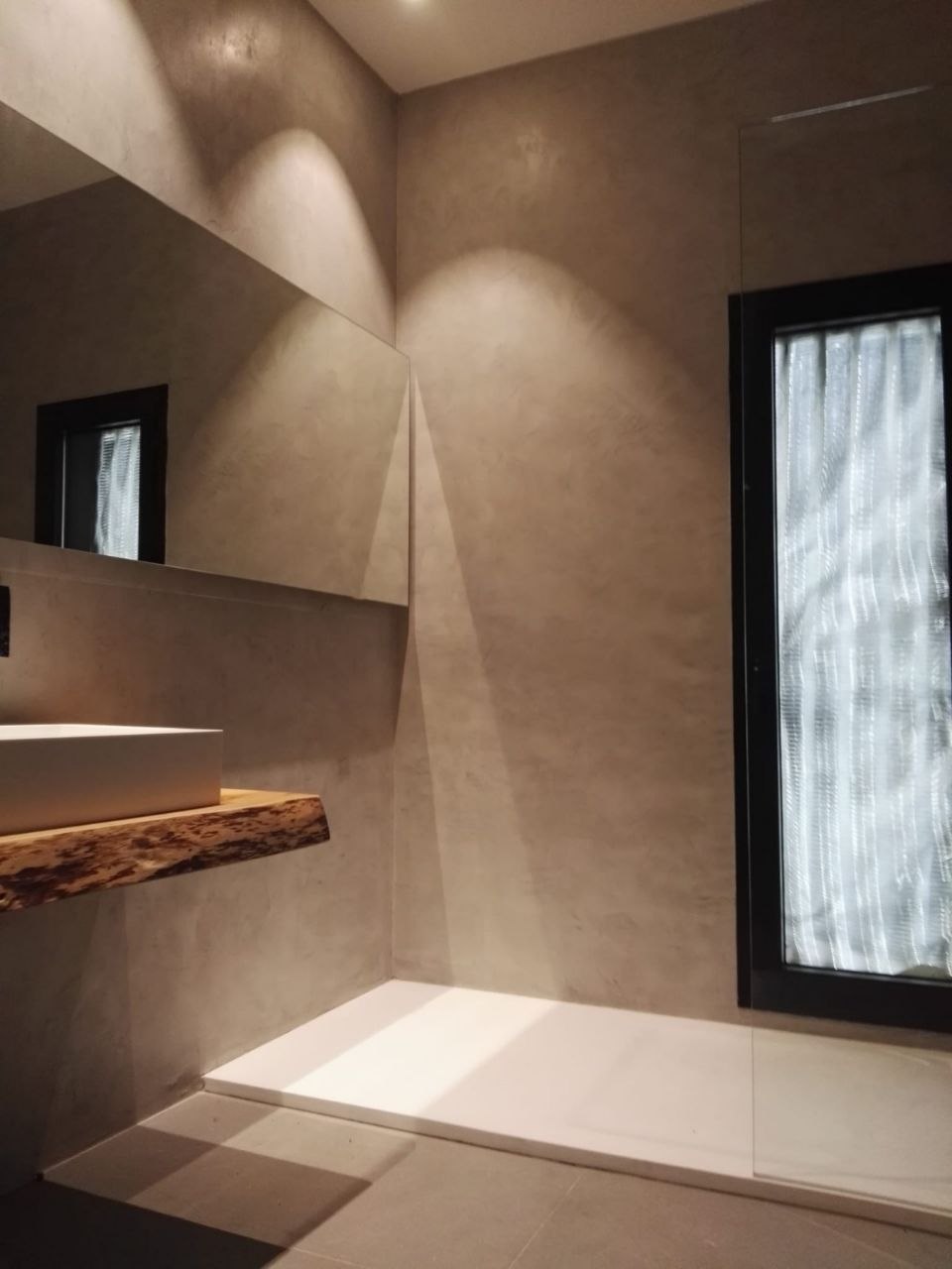 Seamless warm-toned microcement bathroom with a walk-in shower