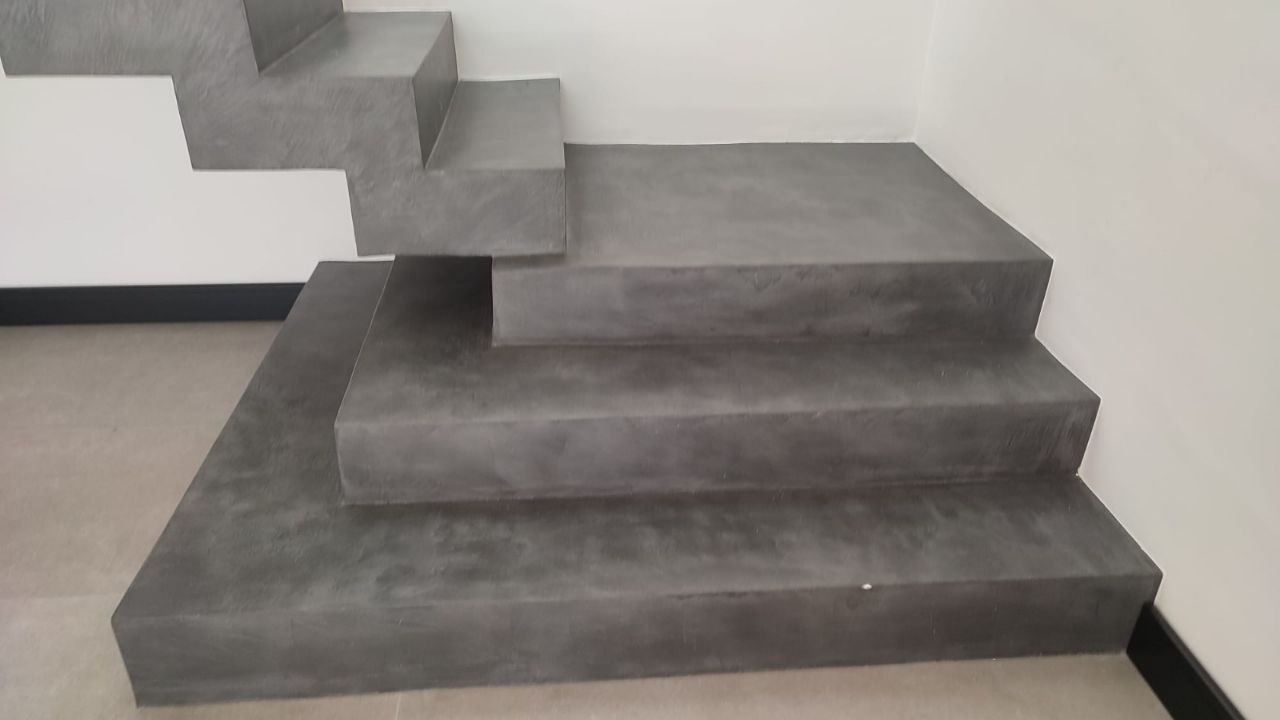 Grey microcement finish flowing across a sculptural staircase