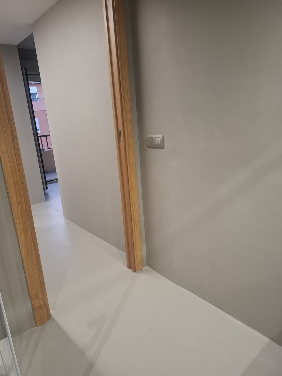 Pale seamless microcement floor flowing through a hallway
