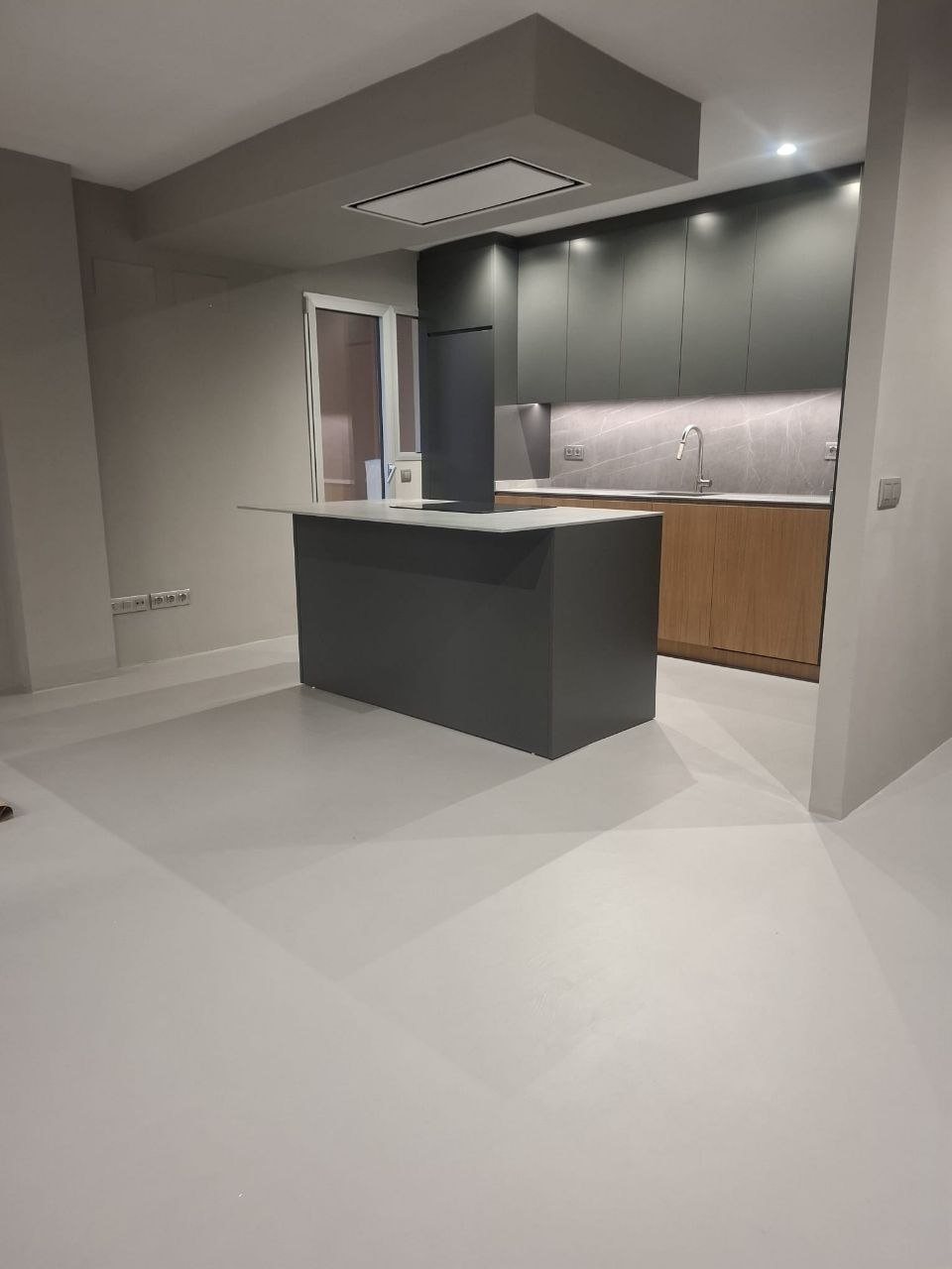 Open-plan kitchen with a seamless grey microcement floor